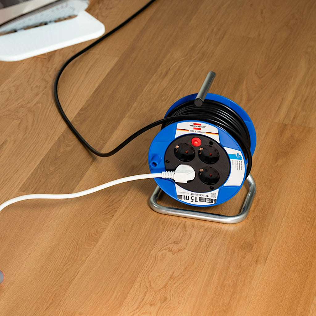 Eine Brennenstuhl Kabeltrommel mit einem eingesteckten Stecker steht auf einem Parkettboden