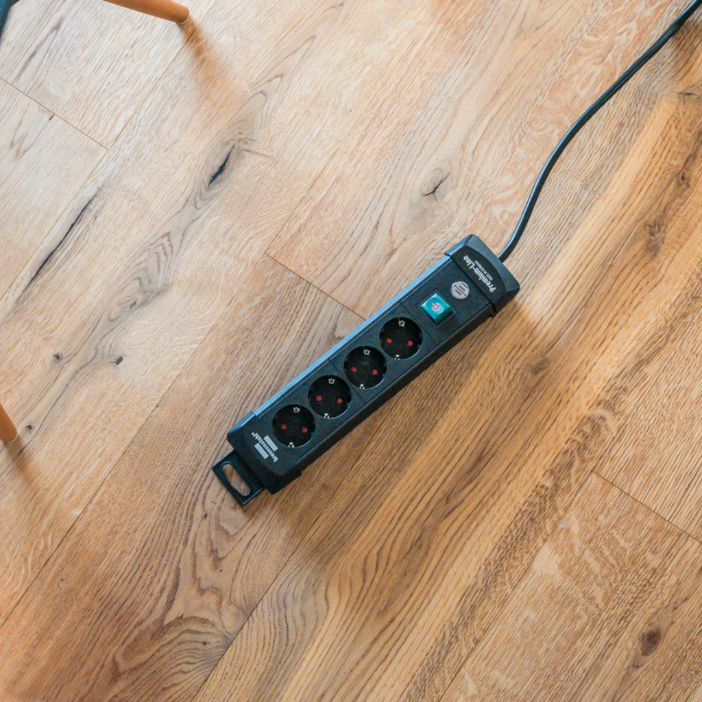 Eine Brennenstuhl Steckdosenleiste 4-fach mit Schalter liegt auf einem Holzfußboden