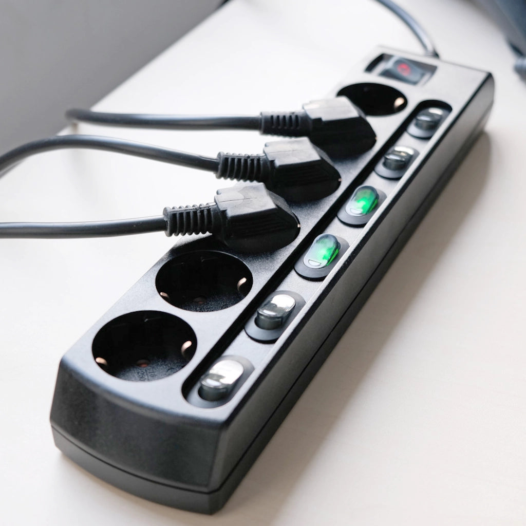 Eine schwarze Brennenstuhl 6-fach Steckdosenleiste liegt auf einem weißen Tisch