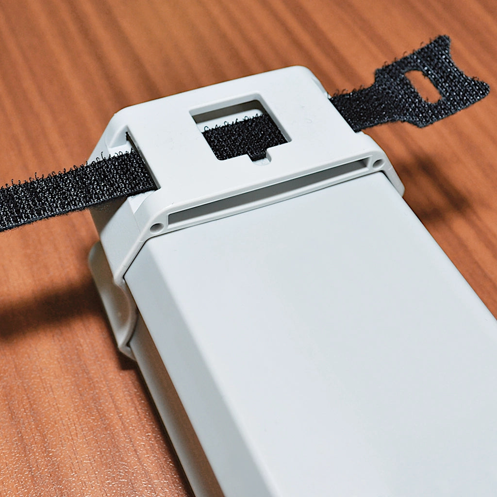 Eine Brennenstuhl Steckdosenleiste liegt auf einem Tisch mit einem Kabelbinder durch die Aufhänge-Vorrichtung gezogen