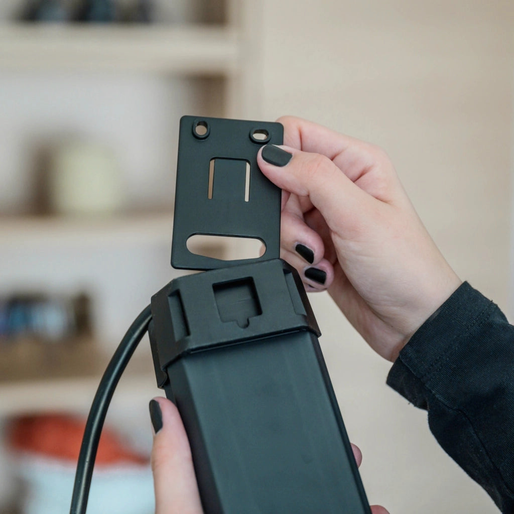 Eine Frau zeigt, dass die Aufhängeöse der Brennenstuhl Steckdosenleiste herausgenommen und gedreht werden kann