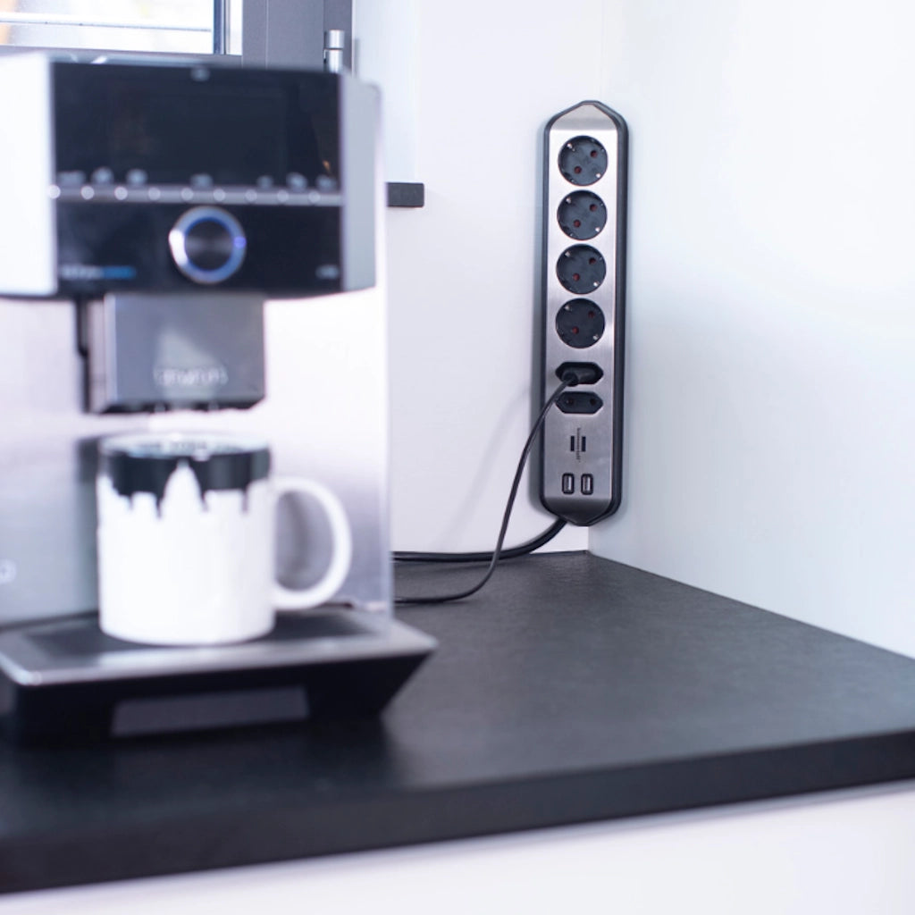 Eine Brennenstuhl Eck-Steckdosenleiste ist in einer Ecke einer weißen Wand vertikal angebracht