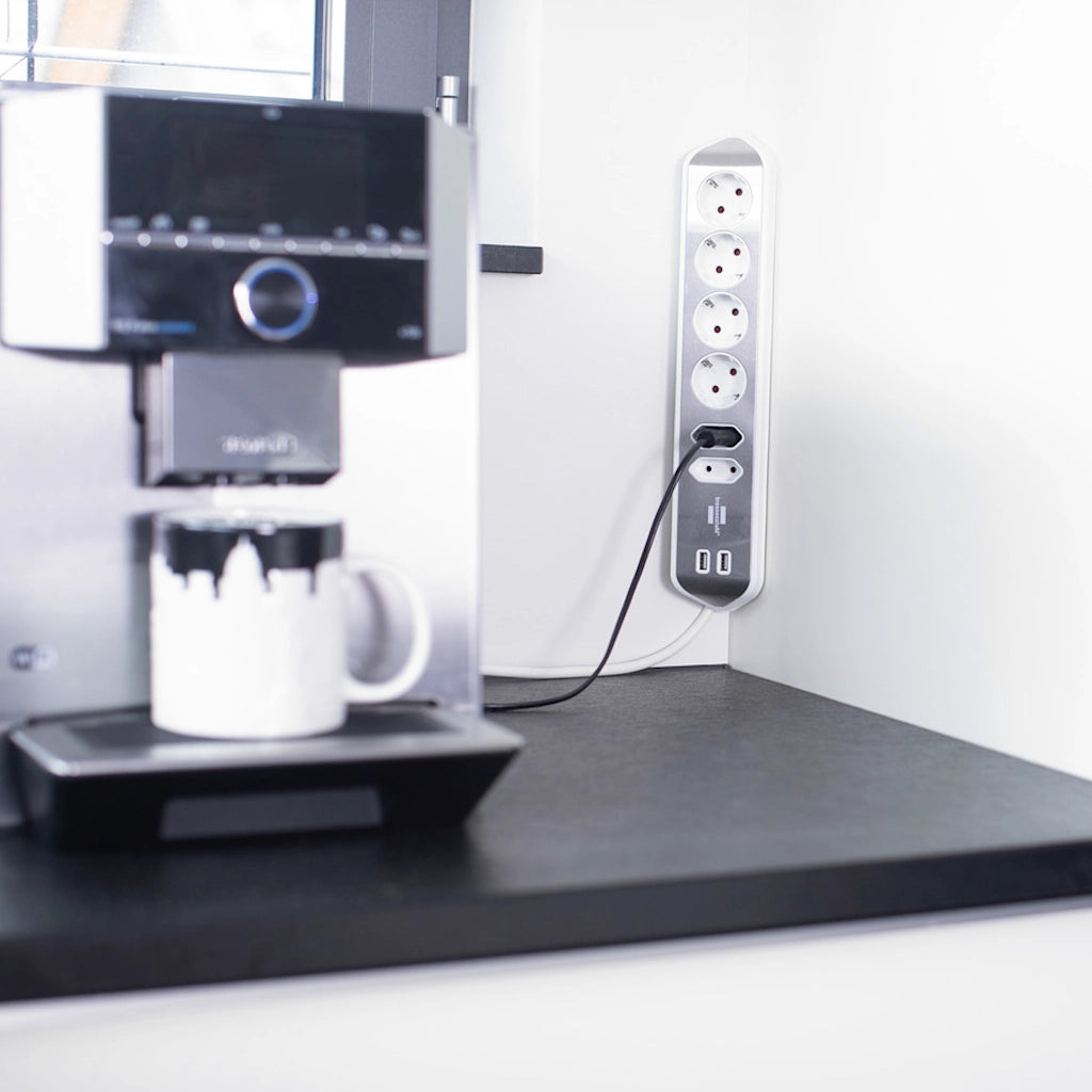 Eine Brennenstuhl Eck-Steckdosenleiste ist in einer Ecke einer weißen Wand vertikal angebracht