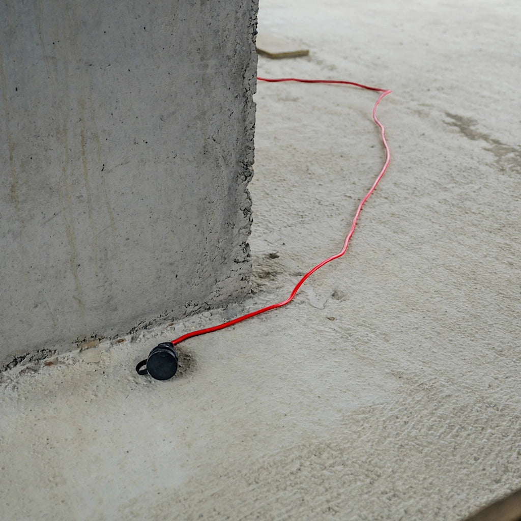 Ein rotes Brennenstuhl Verlängerungskabel liegt ausgelegt auf dem Betonboten eines Rohbaus.