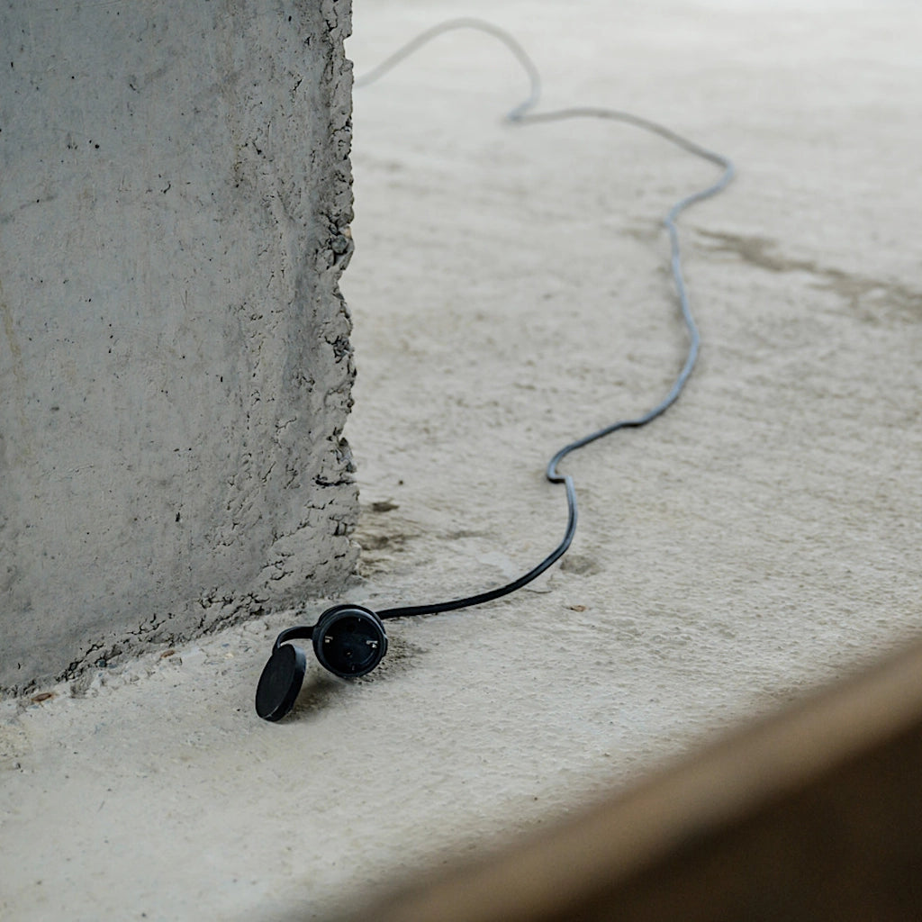 Ein schwarzes Brennenstuhl Verlängerungskabel liegt ausgelegt auf einem Betonboten auf einer Baustelle.