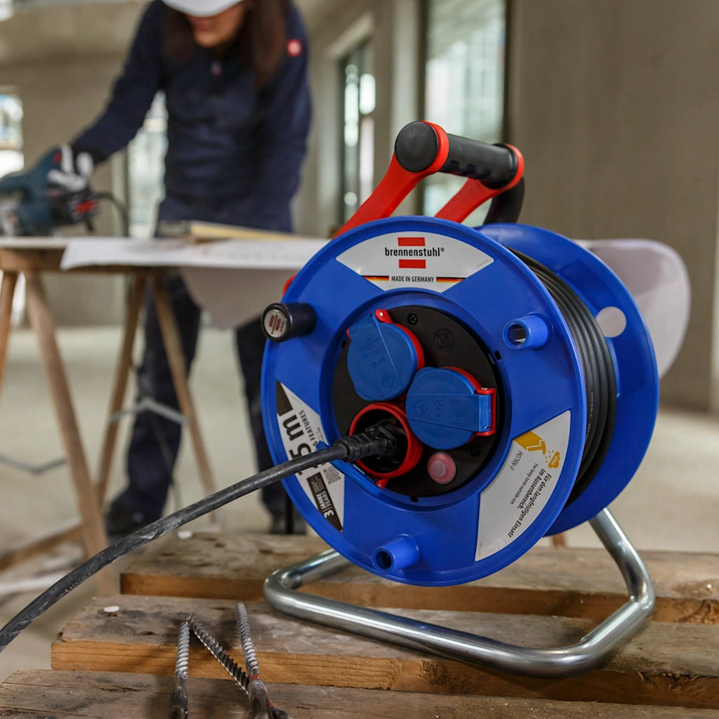 Eine Brennenstuhl Kabeltrommel Garant 3-fach 25m steht auf einem Holzbalken auf einer Baustelle.