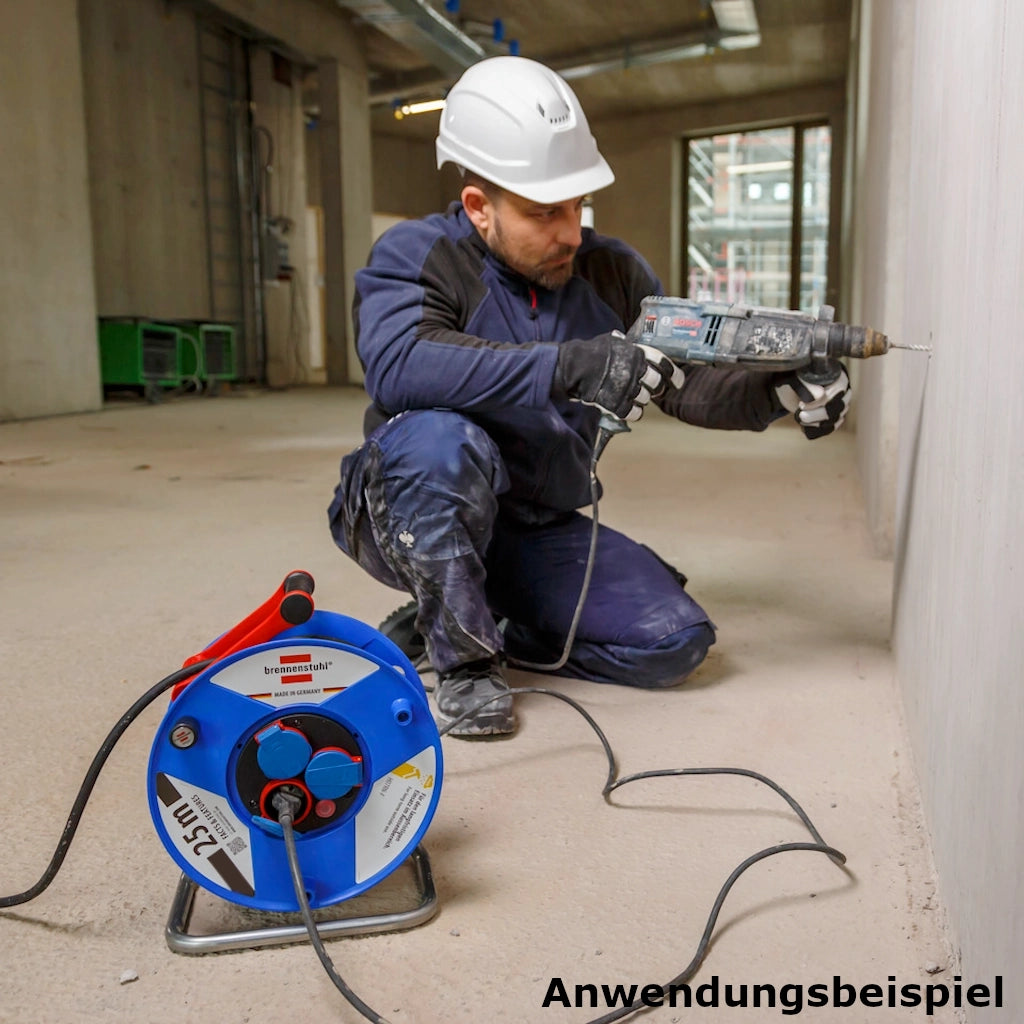 Ein Mann kniet mit einer Bohrmaschine in der Hand vor einer Betonwand und setzt zum Bohren an