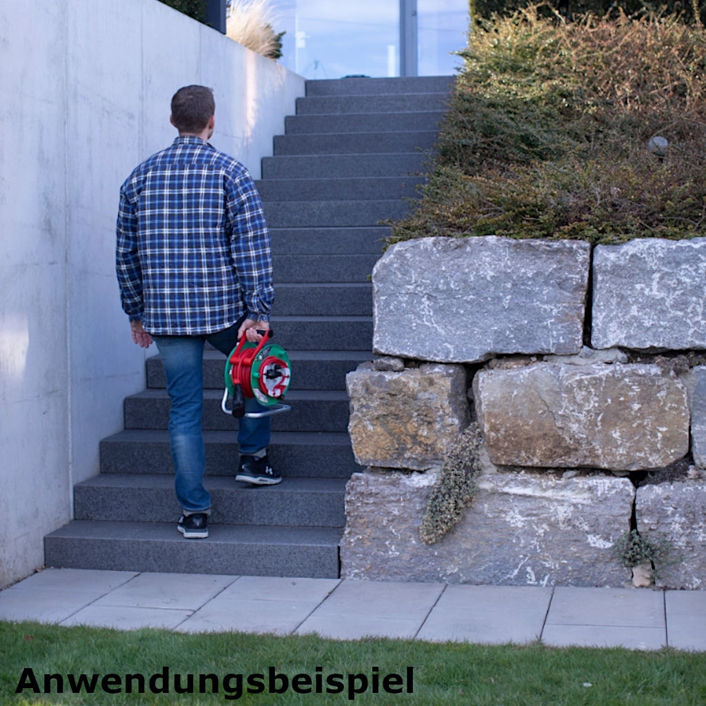 Ein Mann tägt eine Brennenstuhl Kabeltrommel ein Treppe hinauf.