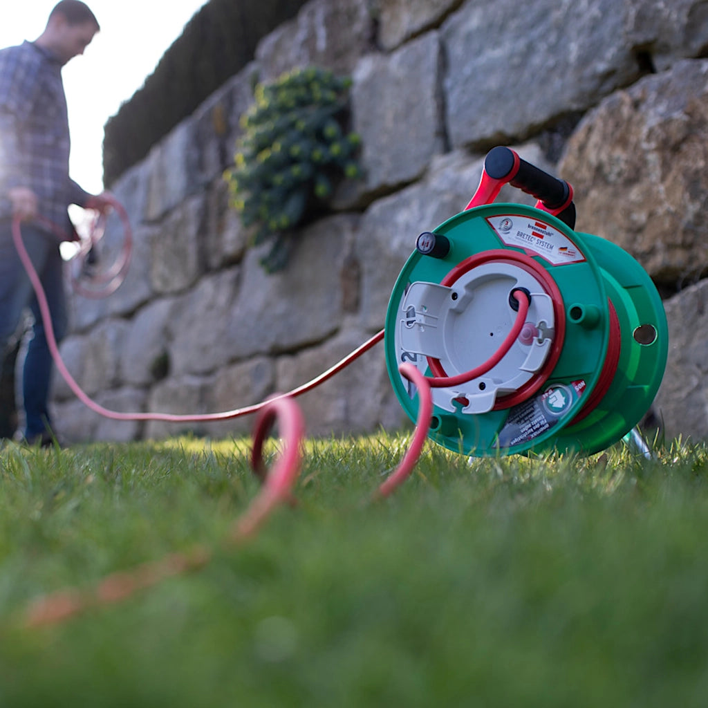 Brennenstuhl Kabeltrommel Garant G 25m IP44 steht auf dem Rasen und ist in Benutzung