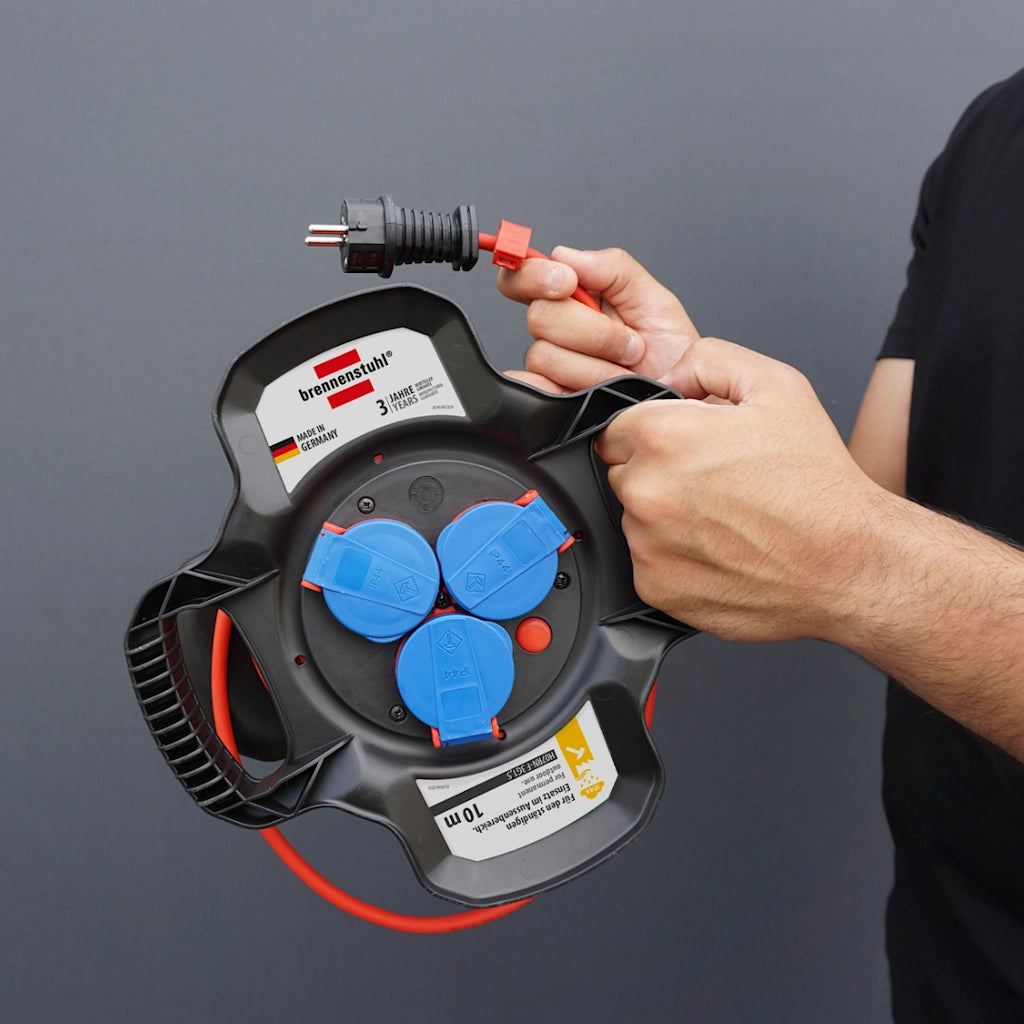 Ein Mann hält eine Brennenstuhl X-Gum Kabeltrommel in der Hand vor seinem Körper