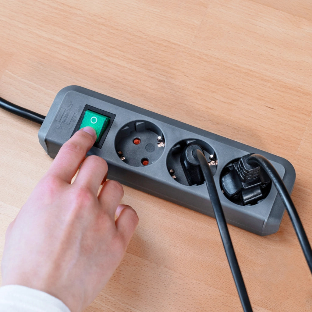 Ein Mann betätigt den Ein- und Ausschalter einer silbergrauen Brennenstuhl 3-fach Steckdosenleiste