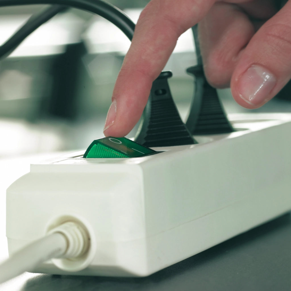 Eine Frau betätigt den Ein- und Ausschalter einer weißen Brennenstuhl 3-fach Steckdosenleiste