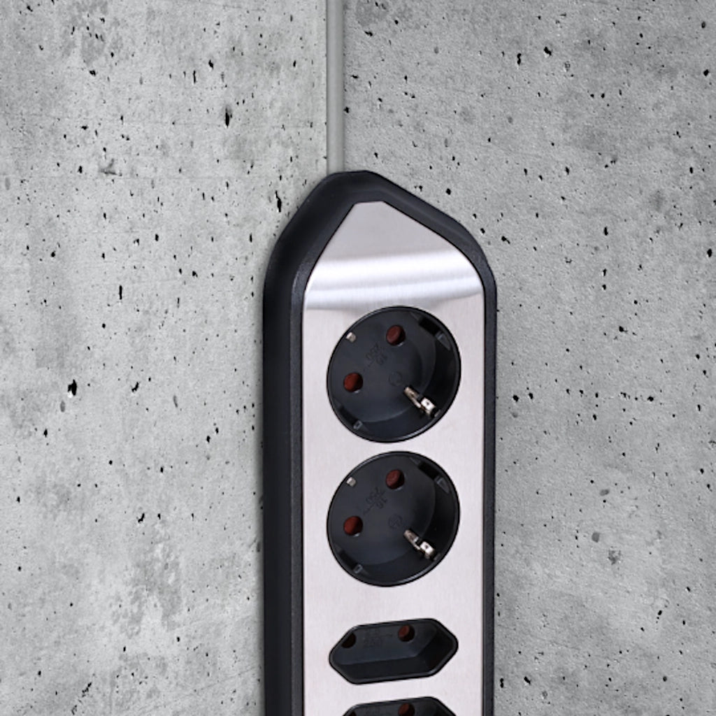 Eine Brennenstuhl Eck-Steckdosenleiste ist an einer grauen Betonwand in der Ecke vertikal montiert