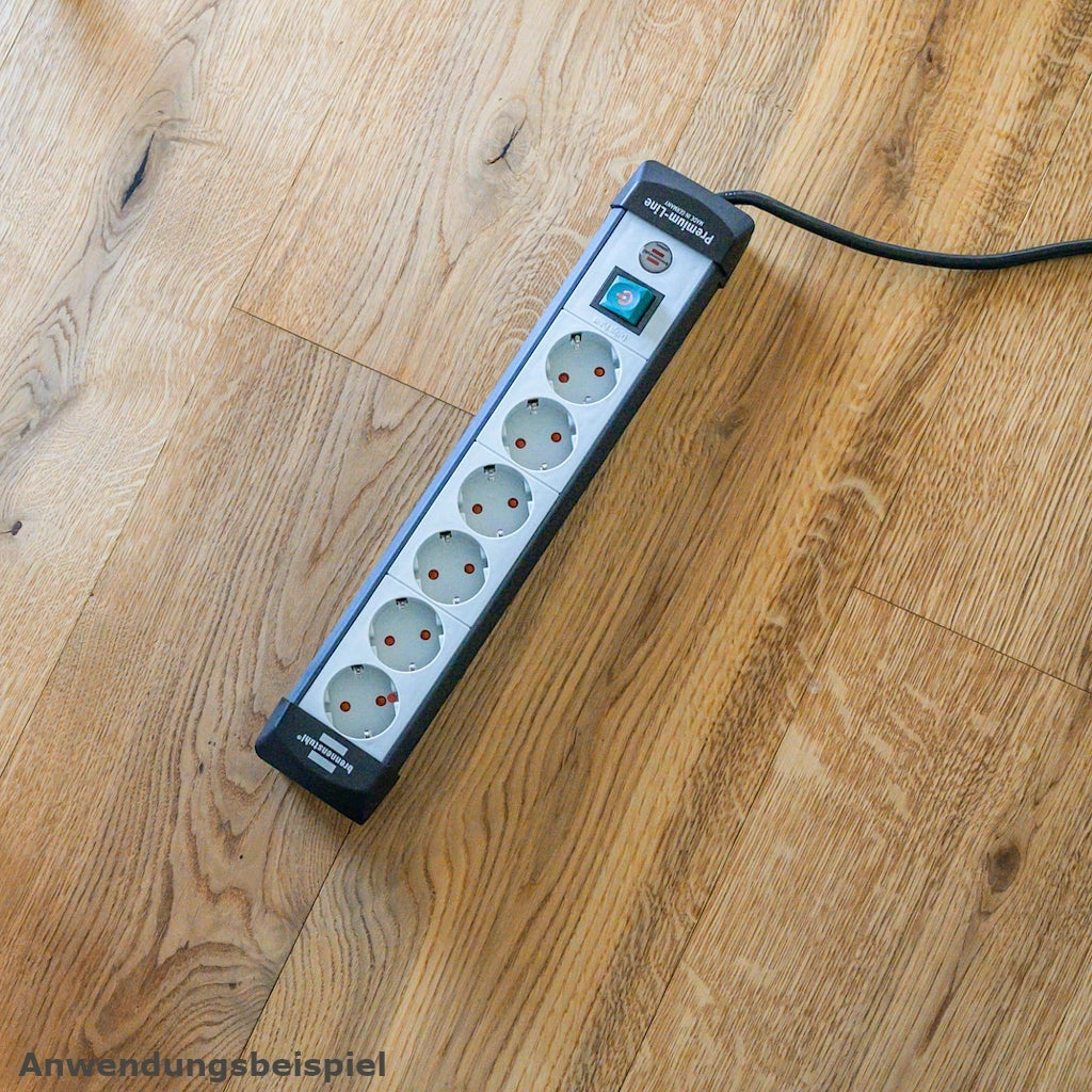 Eine Brennenstuhl Steckdosenleiste 6-fach mit Schalter liegt auf einem Holzfußboden