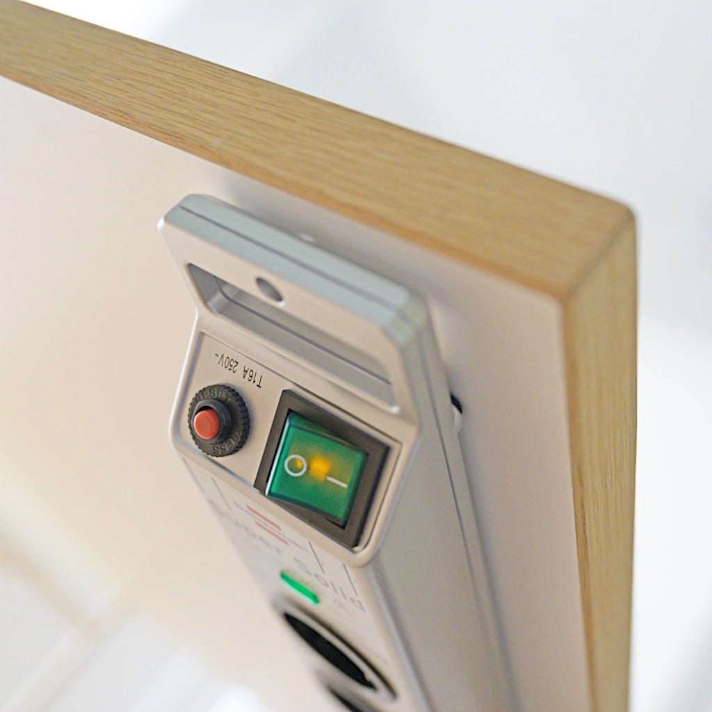 Eine silberne Brennenstuhl Steckdosenleiste mit Überspannungsschutz ist an einer Möbelwand angeschraubt