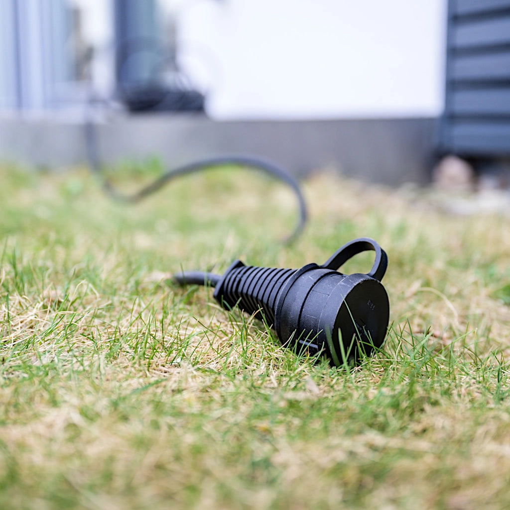 Ein schwarzes Brennenstuhl Verlängerungskabel liegt ausgelegt auf einer grünen Wiese