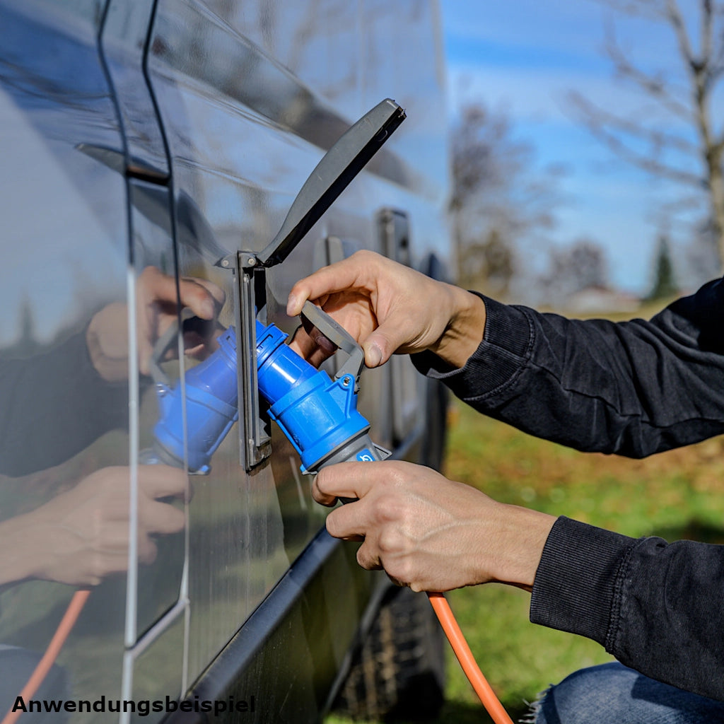 Ein Mann schließt eine Brennenstuhl Camping Verlängerungskabel in orange an ein weißes Wohnmobil an 