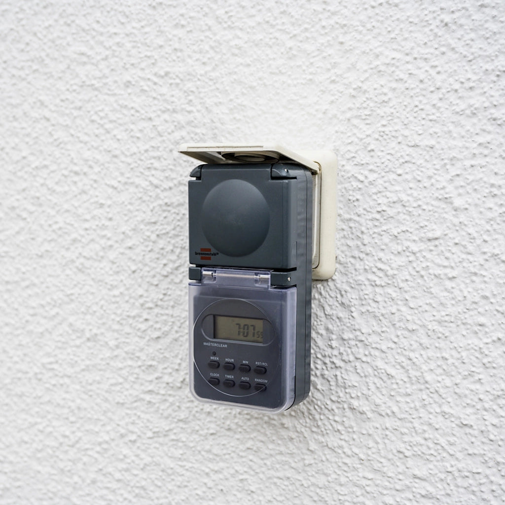 Eine digitale Brennenstuhl Zeitschaltuhr in anthrazit steckt an einer weißen Wand in einer Steckdose