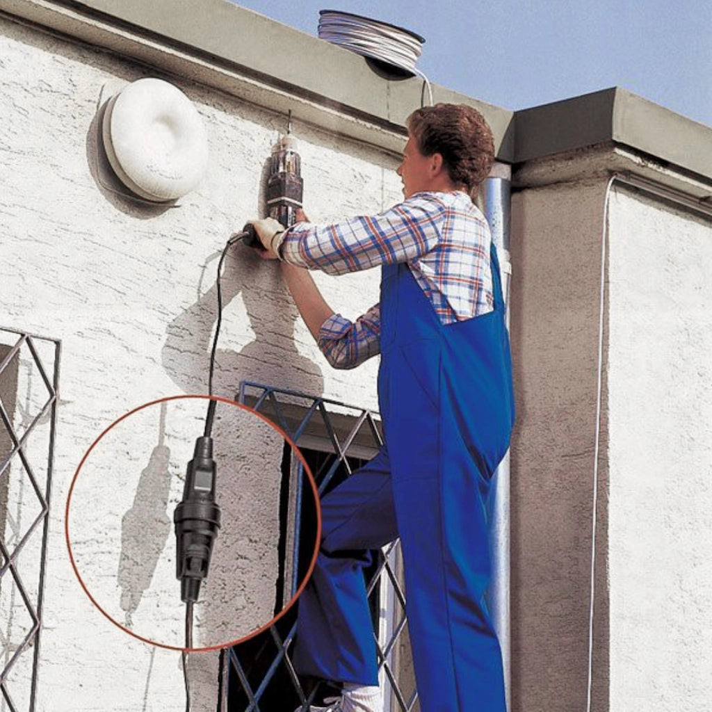 Ein Mann bohrt ein Loch in eine Hauswand und nutzt dabei die verriegelbare Kopp Gummi-Kupplung
